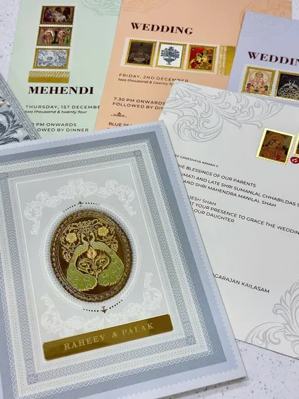 A royal and vintage combination wedding card. This design features a beautiful peacock coin, intricate silver and gold foiling, and inserts with traditional miniature paintings.
