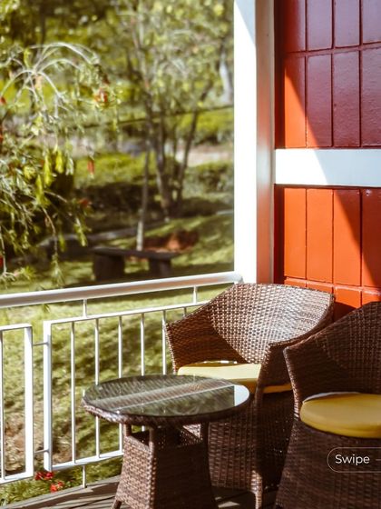 A cozy balcony setting with wicker chairs, perfect for enjoying a morning cup of tea while overlooking the garden and the valley beyond.