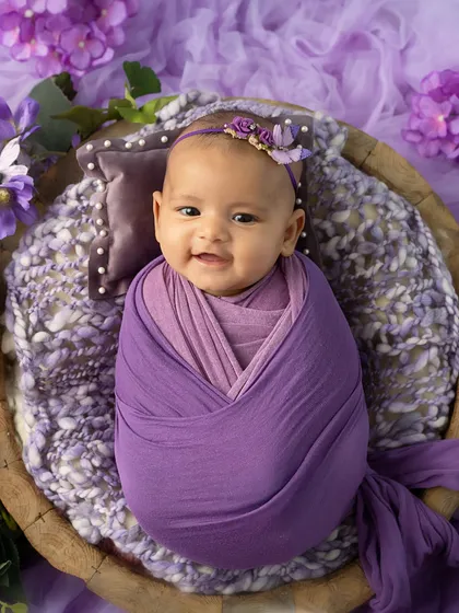 The sweetest smile. This 3-month-old is happy and content, wrapped snugly in a lavender swaddle.