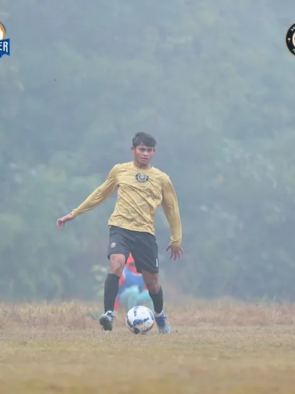 A player on the ball, navigating through the fog. Our commitment to the game is unwavering, no matter the conditions.