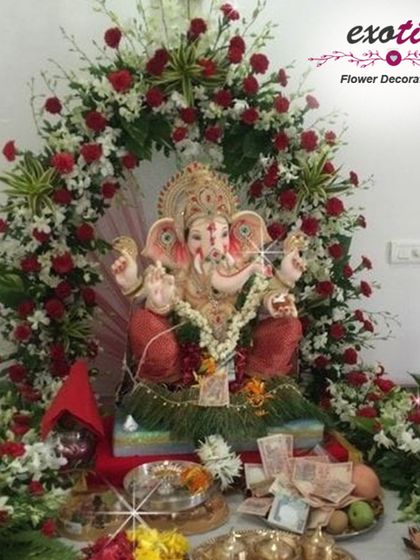 A classic and beautiful floral arch for a home Ganpati setup, made with red roses, white carnations, and lush greenery. This timeless design provides a perfect frame for the idol, enhancing the devotional atmosphere of your pooja space.