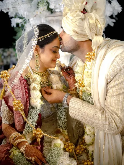 A promise sealed with a kiss on the forehead. The intricate details of the bride's panetar and the groom's sherwani shine in this beautiful shot.