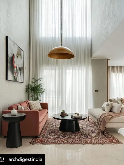 A double-height living room in a modern family home designed by Weespaces, featuring our accent tables and chairs. The neutral palette is punctuated by our pieces, including a terracotta sofa and a caned accent chair, creating a warm and comfortable environment.