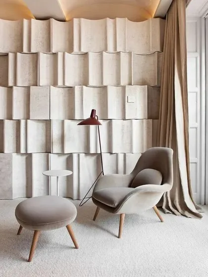 Comfort and sculptural form combine in this reading nook. The soft, curved armchair and the unique textured wall panels show how minimalism can be warm and inviting, creating a perfect corner for relaxation.