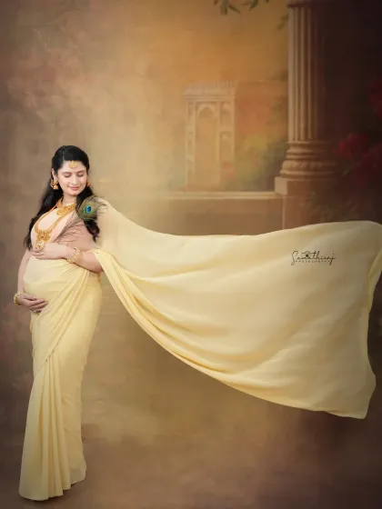 A graceful portrait of a mother-to-be in a flowing yellow saree. The artistic backdrop and her serene pose create a dreamy and elegant image that celebrates tradition.