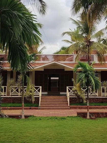 The grand entrance of the "Grid in the Grove" farmhouse, framed by the lush greenery of the coconut plantation. The design invites you into a space that is both a home and a part of the natural world.