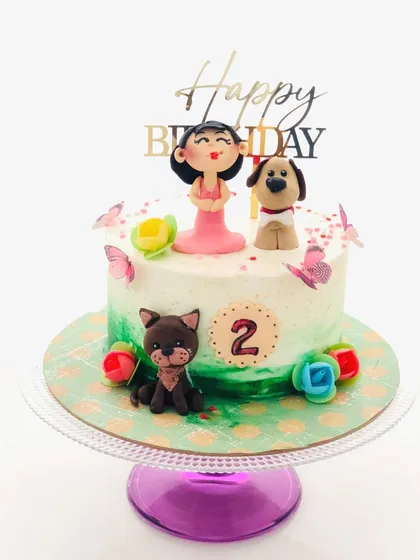 A sweet and simple birthday cake with adorable, hand-sculpted girl and pet dog figurines.