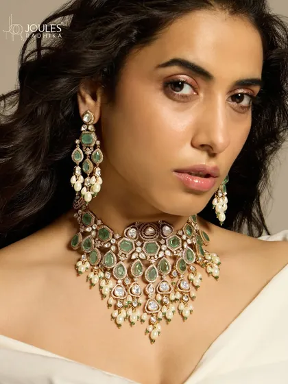 A close-up of the emerald and polki necklace and earring set, as worn by Nimrit Ahluwalia, highlighting the beautiful combination of uncut diamonds and vibrant green stones.