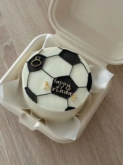 We can bring any hobby or passion to life on a cake. This football-themed bento cake was a huge hit, featuring hand-piped details and custom gold lettering for a fan's special day.