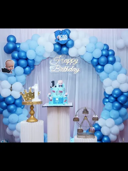 A simple and sweet Boss Baby setup with a blue balloon arch against a white curtain. The themed cake takes center stage on the pedestal.