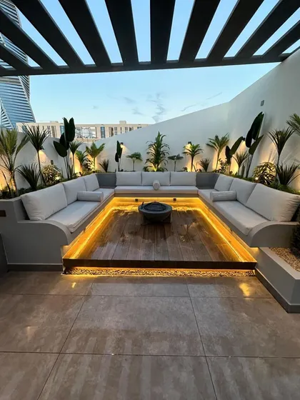 We designed this modern rooftop lounge with a custom sunken seating area to create an intimate and luxurious space for entertaining. The design features integrated perimeter lighting under the U-shaped sofa and strategically placed uplighting on tropical plants to enhance the evening ambiance.