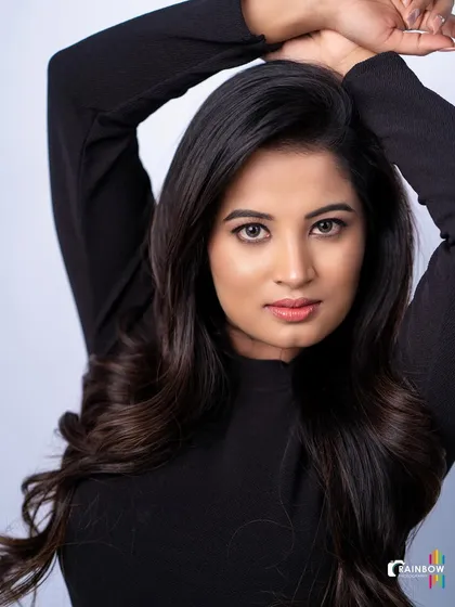 A direct and engaging headshot with a black top and clean background, perfect for an actor's portfolio.