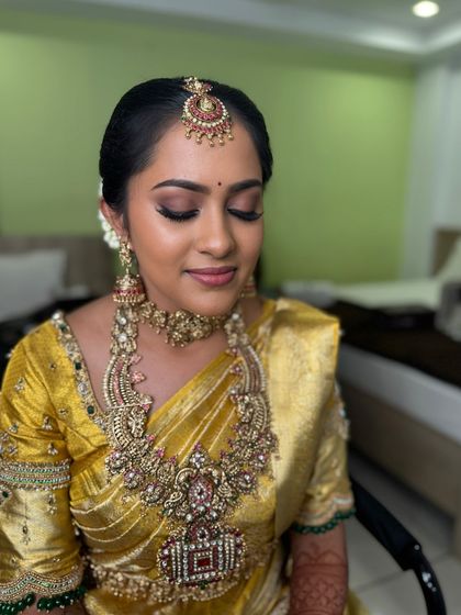 Vani with her eyes closed, showing the detail of her eye makeup. The blended brown and gold shades create a sophisticated and timeless look that complements her golden saree.