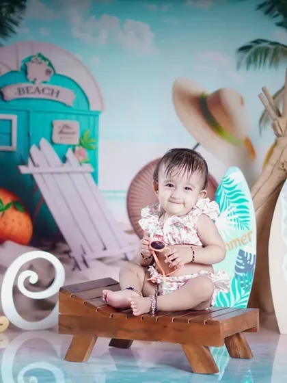 This little beachgoer is ready for her close-up, holding a pair of sunglasses.