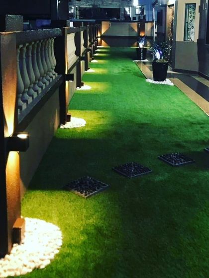 A long terrace walkway at night, featuring artificial grass, inset stepping stones, and uplighting. This shows how I can combine different materials to create a functional and beautiful path.