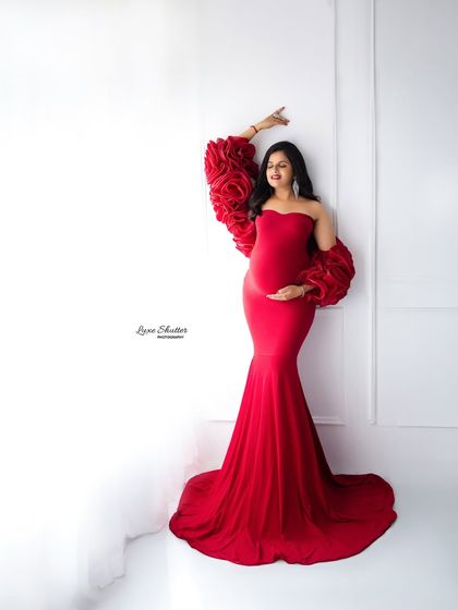 A joyful, dancing pose in the red floral-sleeved gown. This image is full of life and captures the happiness of the moment.