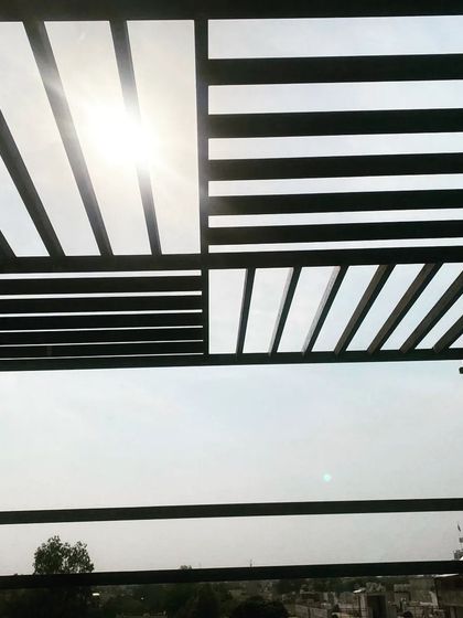 The sun shining through the geometric pattern of the pergola roof.
