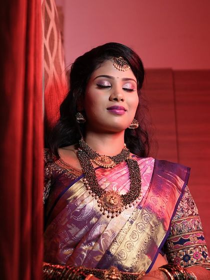 A dramatic and artistic portrait of Aarthi at her reception. The red lighting enhances the bold purple tones of her makeup and saree.
