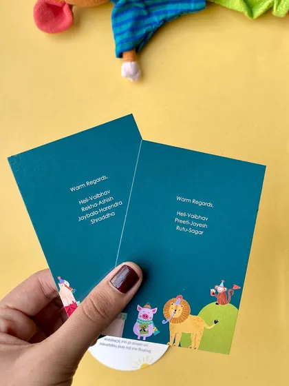 Holding the two-part baby announcement card. The front features the family's warm regards, and the back has the playful animal illustrations. It's a joyful design for a happy occasion.