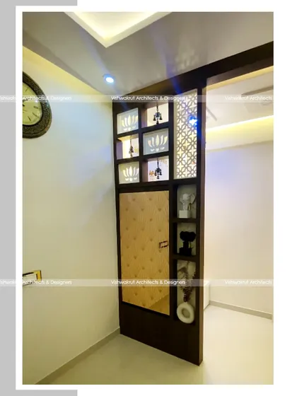 A view of the partition with a foldable dining table in its closed state. It functions as a beautiful decorative element with display niches and jali work, completely concealing the table.