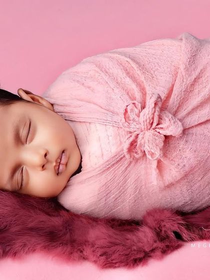 A full-body view of the baby in a pink flower-style wrap, looking like a tiny, precious bud.