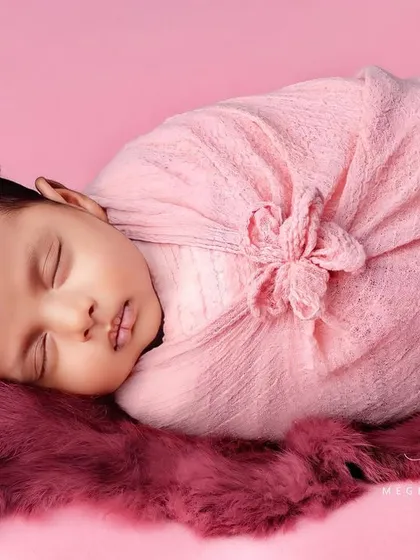 A full-body view of the baby in a pink flower-style wrap, looking like a tiny, precious bud.