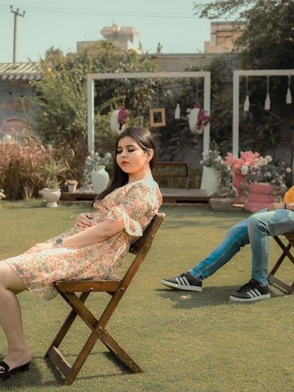 A playful and stylish pre-wedding shot of a couple relaxing in chairs in a garden setting, capturing their cool and casual dynamic.