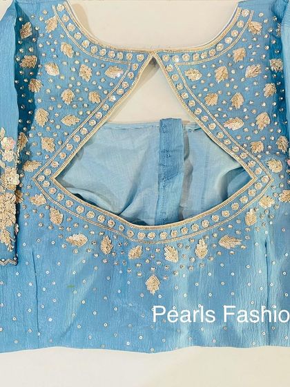 A simple and elegant keyhole back design on a light blue blouse. The leaf-pattern embroidery is done with subtle gold thread and sequins.