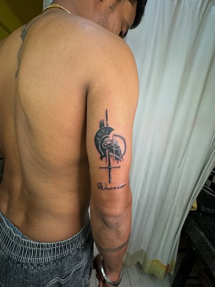 The Spartan warrior tattoo shown on the client's muscular arm, emphasizing the "warrior" theme.