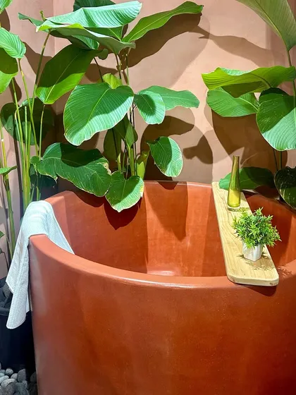 A Japanese-style soaking tub made of terracotta-colored concrete by Crete Kala Studio. This piece combines a modern material with a traditional form, creating a unique and inviting bathing experience.
