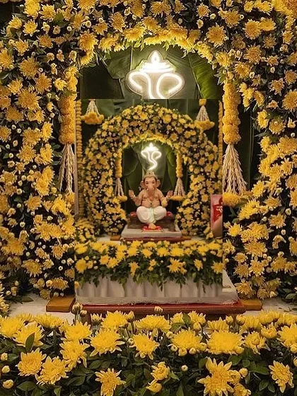 An immersive Ganpati decoration made entirely of yellow chrysanthemums. The double-layered floral arch with neon Ganesha signs creates a divine glow, making the whole setup feel like a temple of flowers.