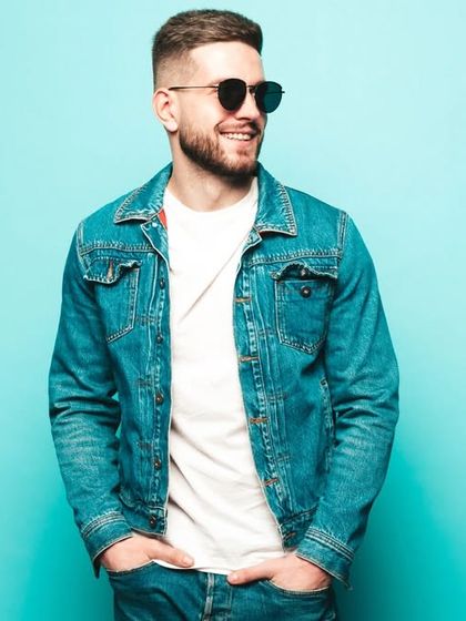 A classic shot of a model in a denim jacket and white t-shirt against a bright blue background, creating a timeless and appealing fashion image.