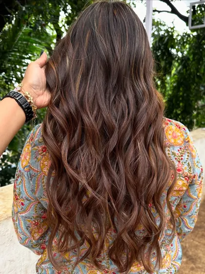 Getting her holiday-ready with a rich blend of copper and caramel highlights. This warm, wavy style is perfect for a festive getaway.