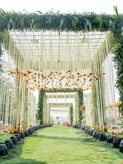 For this traditional wedding, I designed a grand entrance tunnel framed with lush greenery and adorned with hanging floral strings and marigolds. The terracotta urns add an earthy, rustic touch to the magnificent structure.