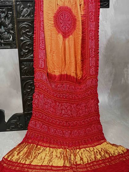 A fiery red and orange Bandhani saree. The crushed texture and vibrant colors are characteristic of this traditional craft, making it a perfect choice for festive occasions.