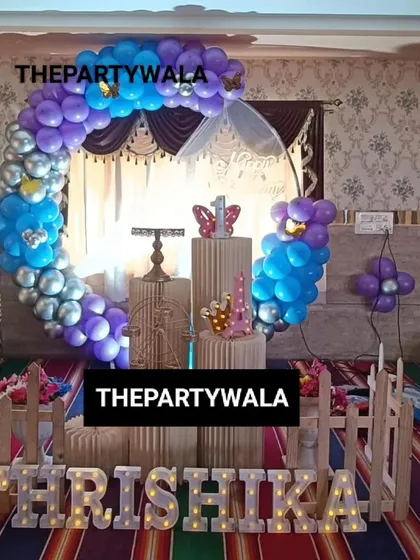 A blue, purple, and silver balloon ring. The light-up name sign and picket fence create a lovely and complete photo corner.