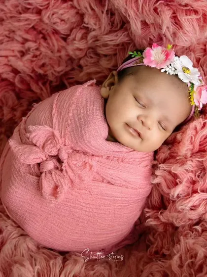 A smiling baby in a pink wrap on a matching textured rug. This shows how to create a simple yet impactful monochromatic setup.