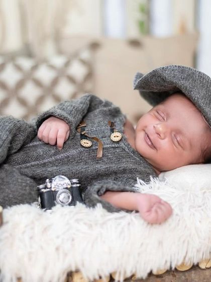 A sweet, smiling newborn dreaming away. Capturing these sleepy smiles is one of the most rewarding parts of our job, and it requires patience and a gentle touch.