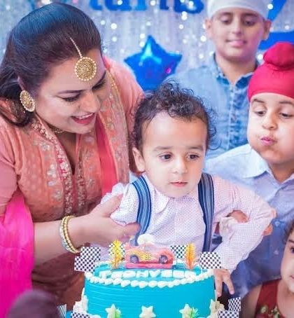 The birthday boy gets ready to blow out the candles on his car-themed cake, surrounded by family and friends.