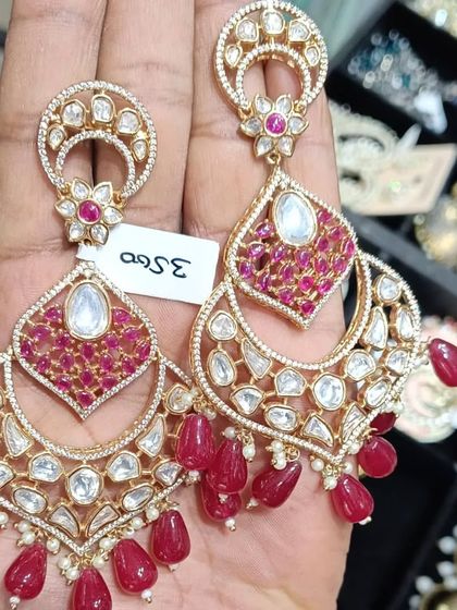 A pair of chandbali earrings with intricate ruby-colored stone work and uncut kundan. These are very elegant and perfect for a wedding.