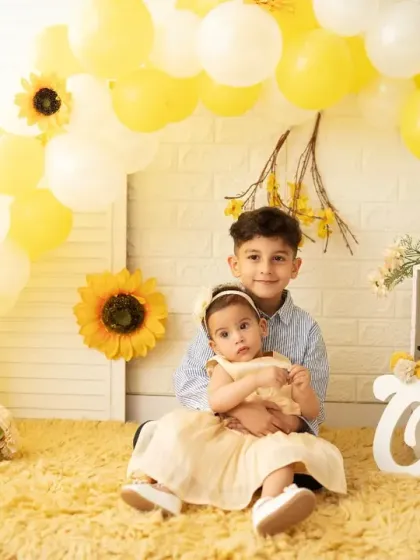 An older brother holds his baby sister during her first birthday photoshoot. We love capturing sibling bonds and including the whole family in the celebration.