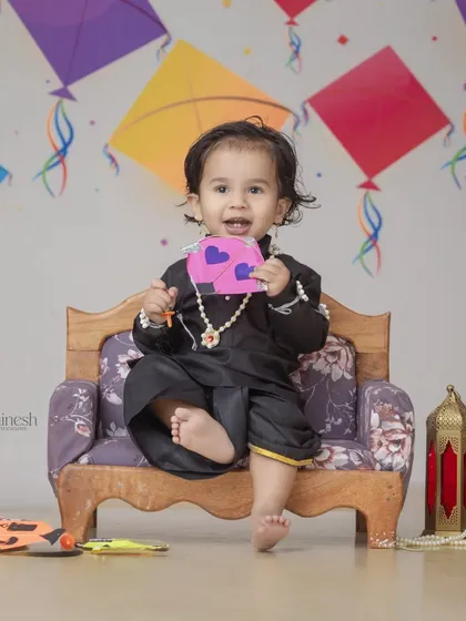 A happy moment from the Makar Sankranti session, with the baby boy showing off his little pink kite. The simple setup keeps the focus on his adorable expression.