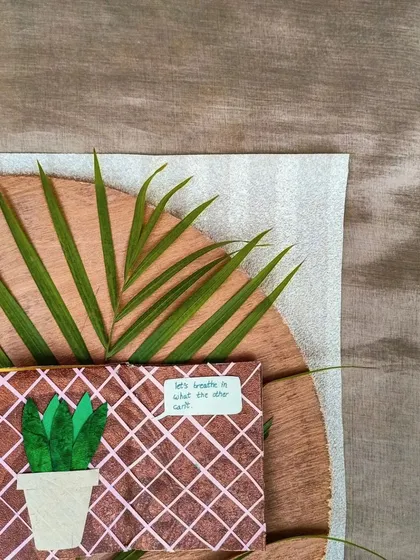 A mini journal page with a plant theme, styled with a palm leaf on a wooden board.