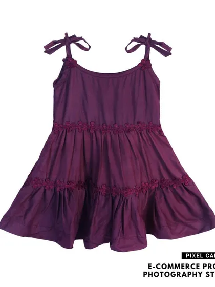 A flat lay of a tiered purple baby frock with shoulder ties, shot on a white background.