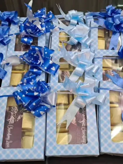 An assortment of budget-friendly chocolate boxes with different blue ribbon styles. I can customize these small details to match your preferences.