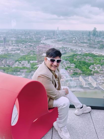 A seated pose on a modern red chair, creating a striking contrast with the panoramic view of London.