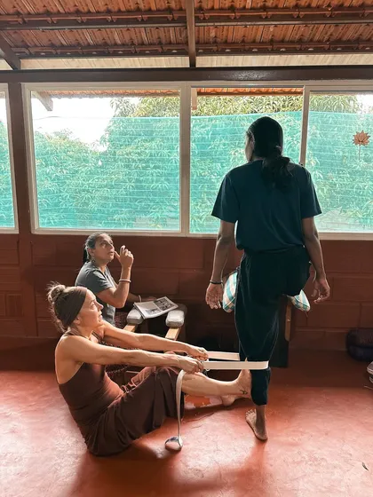 This image captures a moment of learning how to use straps for leg alignment. This technique is crucial for protecting the knees and hips in seated postures, a core focus of our yoga therapy training.