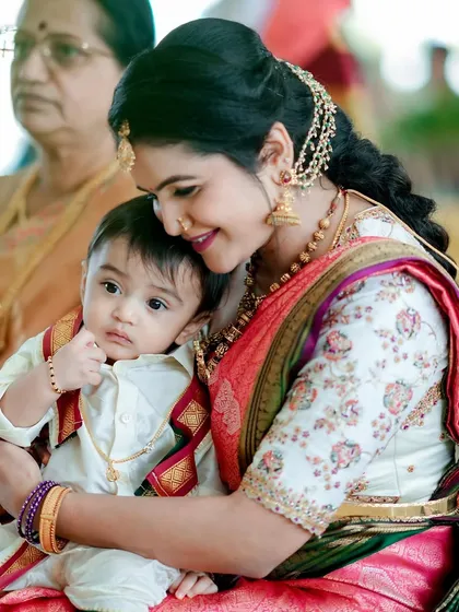 A heartwarming moment between a mother and her child. She is wearing a custom white blouse with floral embroidery, showing that my designs are perfect for all of life's special occasions.