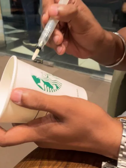 Starting the coffee cup art project. I use a water brush pen to begin laying down the initial sketch on the cup's surface.