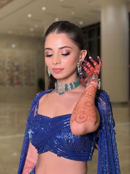 Another angle showcasing the beautiful henna and the contrast between the bold blue outfit and the soft, glamorous makeup.
